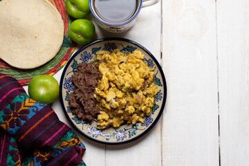 Scrambled eggs with green sauce and refried beans on white background. Mexican food