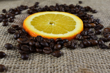 Pokrojone plasterki pomarańczy i ziarna niezmielonej kawy.