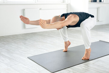 young yoga man doing various yoga poses indoors, stretching body for wellbeing and having muscular strong body