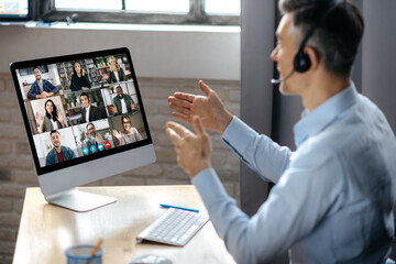 Virtuak business meeting online. Successful businessman is negotiating with multiracial business partners on a video conference using a computer while sitting at his workplace - Powered by Adobe