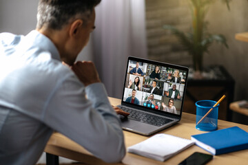 Fototapeta premium Online video communication. A successful adult businessman uses a laptop for video conference with business partners. A manager or ceo is sitting at his desk, talking on a video call with colleagues