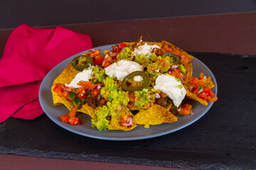 Nachos, tortilla chips, home made guacamole, salsa, chilli con carne, soured cream, grated cheese and jalapeno peppers, landscape