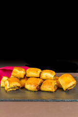 Home made sausage rolls on dark slate mat red napkin, portrait, copyspace.