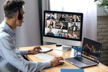Business meeting online. Successful businessman is negotiating with multiracial business partners on a video conference using a computer while sitting at his workplace