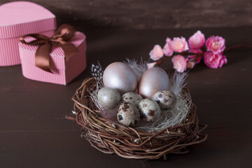 Easter nest with eggs on brown bakcground with pink blossom  flowers and gift boxes