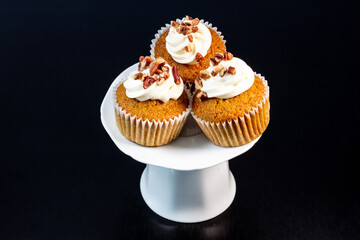 tres madalenas de nuez con crema batida en soporte blanco con fondo negro