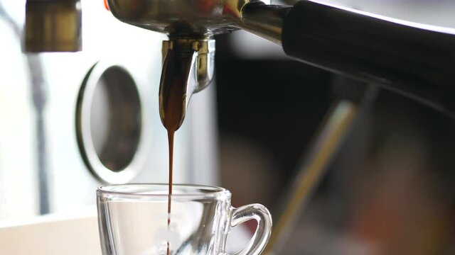 Pouring coffee stream from professional machine in cup. Barista making double espresso, using filter holder. Flowing fresh ground coffee. Drinking roasted black coffee in the morning