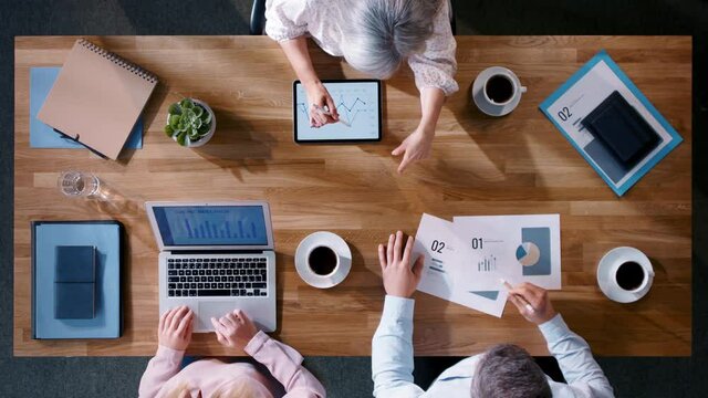 Top view of business people working on computer at desk with paperwork in home office.