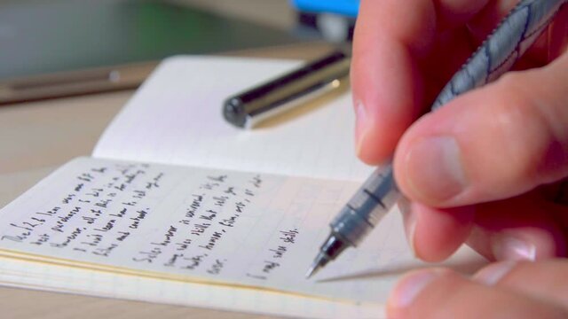 Writing in notebook, close-up on human hands