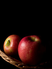 Fruit basket still life with fresh fruits in a wicker basket on black background with copy space