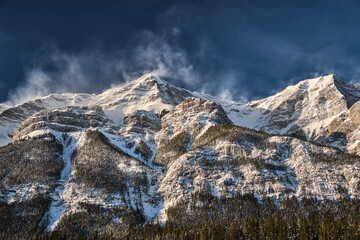  Snow blowing off montain peaks by strong wind.  Blizzard in mountains. Spray Valley Povincial...