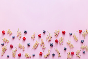 Colorful pattern of blueberries, currant berries white, raspberries on pastel pink background. Flat lay, top view, copy space.