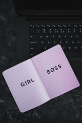 equal opportunities Girl Boss text on top of pink notebook on laptop keyboard on black background