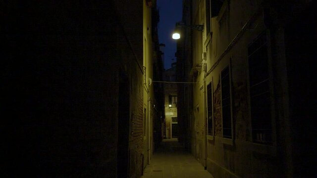 Dark narrow street in Venice, Italy at night