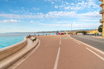 Tourists and locals enjoy the seaside pedestrian access at the Bay of Angels on the French Riviera in Nice France with the #Ilovenice sign in view.