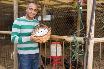 Portrait of positive man farmer with a basket of chicken eggs © JackF