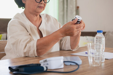 Sick senior woman hold pills bottle and read medicine prescription label and looking at medicine...