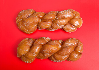 Flat lay top view of two glazed twist cinnamon rolls. Bright red background.