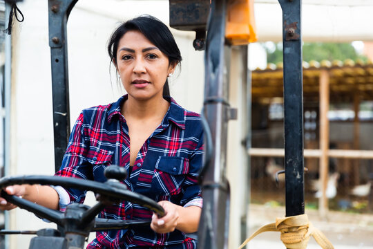 latino colombian woman forklift worker operator driving vehicle at warehouse