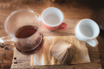 A mug of drip coffee with lens blur effect of 2 cups on wooden table included a wet coffee in cone filter as a prop