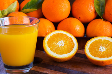 Fresh orange fruit whole and sliced on a cutting board and glass of fresh orange juice cocktail