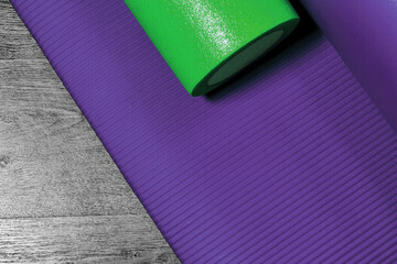 Purple fitness mat and foam roller ready for pilates in the gym. Sports and recreation backgrounds