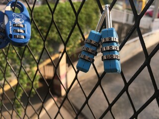 A pair of padlocks on hanging on metal net fence for loving representation.