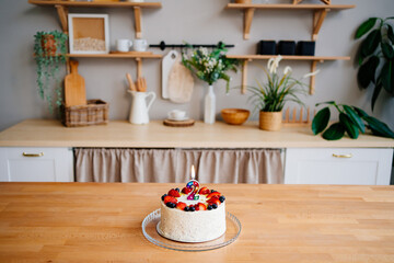 cake with candle number two and fruit on table on Scandinavian-style kitchen 