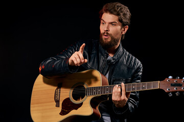 A man with a guitar in his hands leather jacket music performance rock star modern style dark background