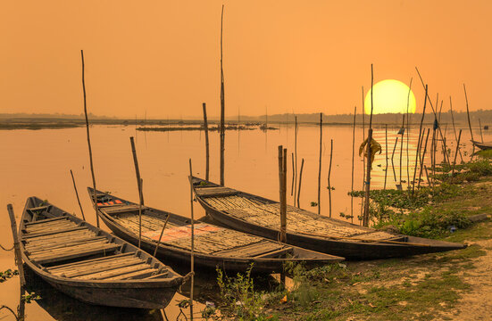 Wooden fishing boats lined up at river bank at sunset at a rural village in Bardhaman district of West Bengal India
