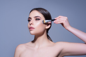 Fototapeta premium Makeup and cosmetics. Woman with makeup brush. Skincare. Visage. Beauty treatments.