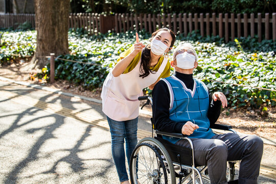 ウイルス感染対策をした介護士の女性と車椅子の高齢男性