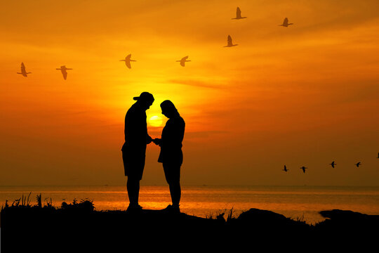 silhouette couple stand facing each other and promise to take care forever with sun dawn sea scape nature background