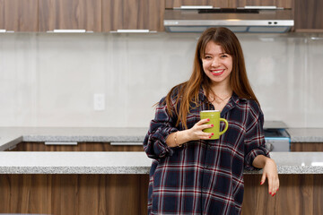Mujer latina tomando café por la mañana en la cocina de su departamento