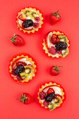 Tartles with fruits and berries on red background