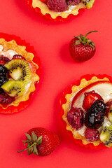 Tartles with fruits and berries on red background