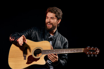 Obraz premium A man with a guitar in his hands leather jacket music performance rock star modern style dark background