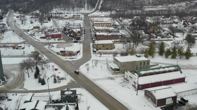 Small American style winter town with cars driving on street in aerial
