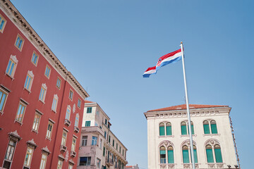 National croatian flag against sky. Beautiful cityscape postcard with Split town architecture.