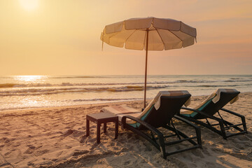 Sun umbrellas and chairs on tropical beach with sunset - obrazy, fototapety, plakaty