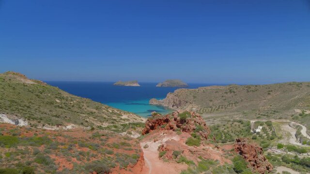 Flying Past Dirt Road and Towards a Bay Surrounded by Cliffs in Milos Greece