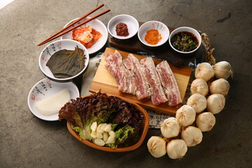 밑반찬과 생돼지고기가 있는 상차림 Table set with side dishes and raw pork