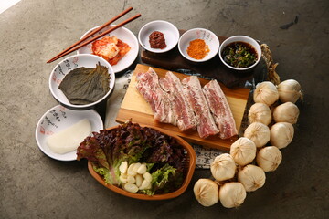 밑반찬과 생돼지고기가 있는 상차림 Table set with side dishes and raw pork