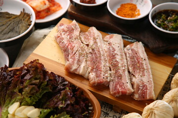 밑반찬과 생돼지고기가 있는 상차림 Table set with side dishes and raw pork
