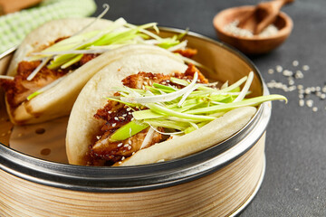 Bao bun with hoisin chicken. Bamboo steamer on dark slate table. Chinese, asian, authentic food...