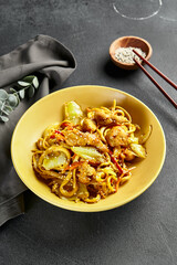Curry Udon Noodles. Asian curry udon in yellow plate with wooden chopstick on dark slate table. Asian, authentic food concept