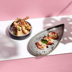Restaurant seafood - Shrimp Grill Seafood Plate. Appetizer food plate on white table with pink wall. Day sunlight with hard shadow of monstera palm leaves. Summer or spring food concept.