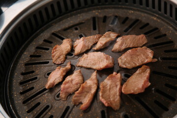 The beef ribs are being cooked on a black grill 검은색 불판에 소고기 갈비살이 익어가고 있는 모습