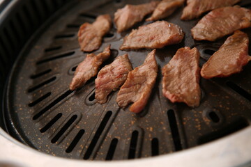 The beef ribs are being cooked on a black grill 검은색 불판에 소고기 갈비살이 익어가고 있는 모습
