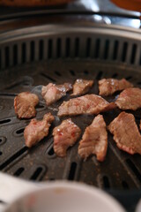 The beef ribs are being cooked on a black grill 검은색 불판에 소고기 갈비살이 익어가고 있는 모습